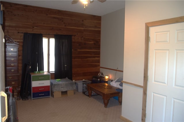 carpeted bedroom featuring ceiling fan and wood walls