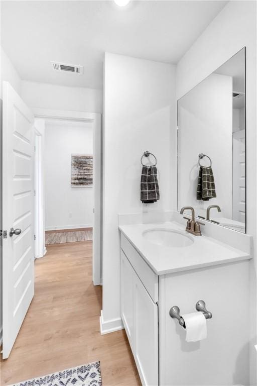 bathroom with visible vents, vanity, baseboards, and wood finished floors