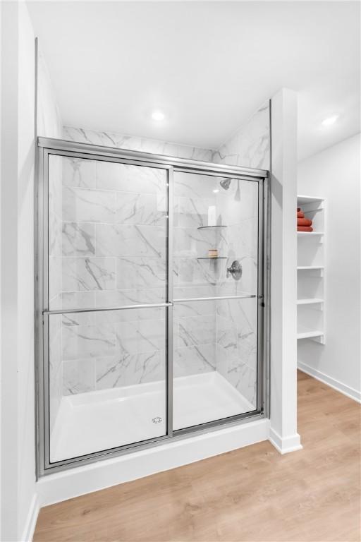 bathroom featuring a stall shower, baseboards, and wood finished floors