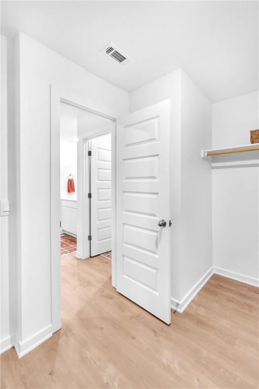 corridor featuring visible vents, baseboards, and light wood-style floors