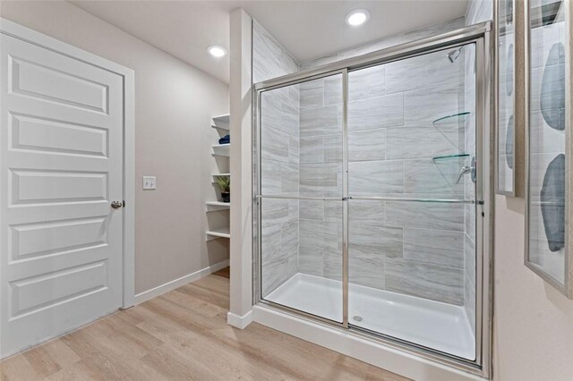 bathroom with a shower with door and hardwood / wood-style floors