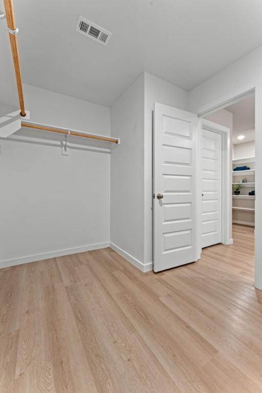 walk in closet with light hardwood / wood-style floors