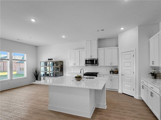 kitchen with white cabinetry, a center island with sink, and appliances with stainless steel finishes