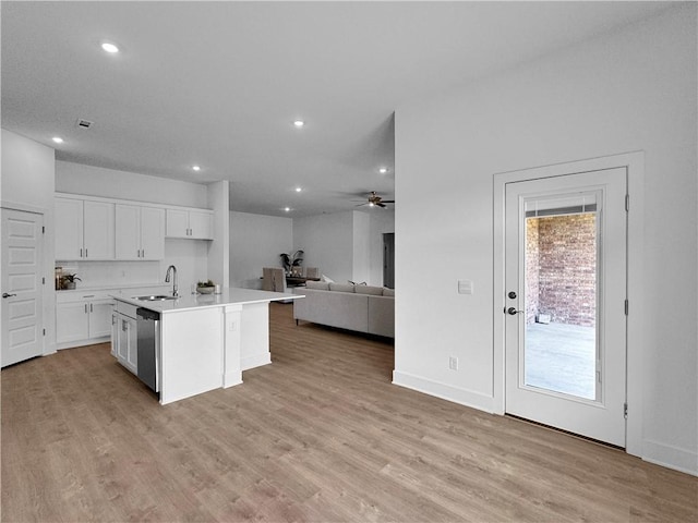 kitchen featuring an island with sink, light wood-type flooring, sink, and white cabinetry