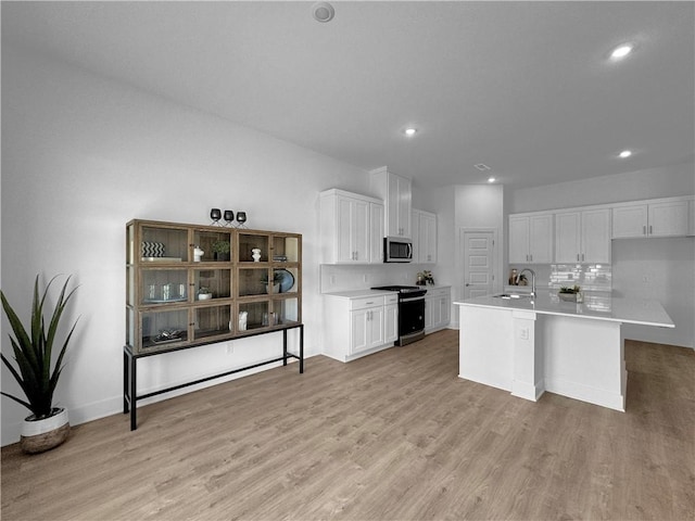 kitchen featuring white cabinets, sink, a kitchen island with sink, appliances with stainless steel finishes, and light hardwood / wood-style floors