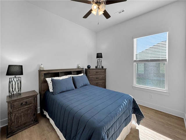 bedroom featuring ceiling fan, light hardwood / wood-style flooring, and multiple windows