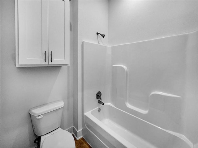 bathroom featuring hardwood / wood-style floors, washtub / shower combination, and toilet