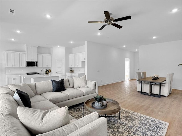 living room featuring ceiling fan and light hardwood / wood-style flooring