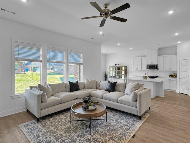 living room with light wood-type flooring and ceiling fan