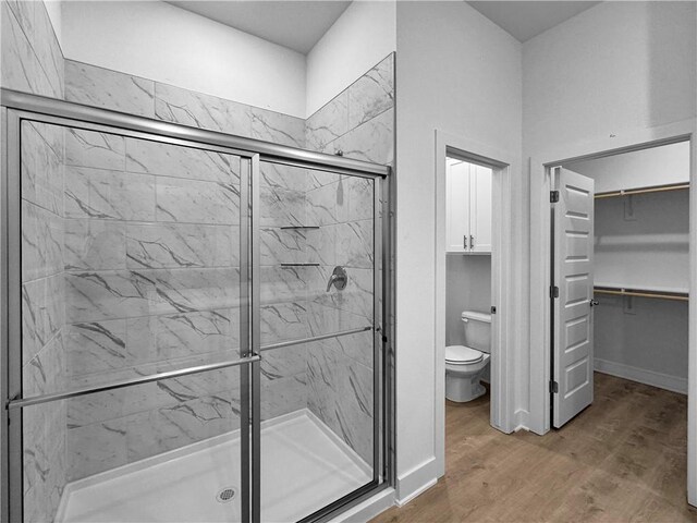 bathroom with hardwood / wood-style floors, a shower with door, and toilet