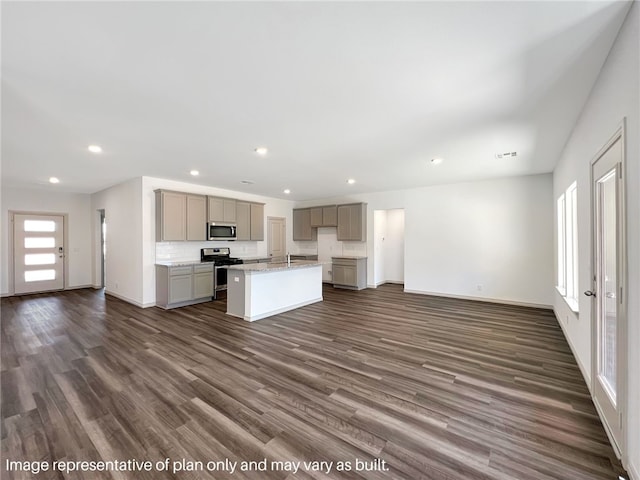 kitchen featuring dark hardwood / wood-style floors, gray cabinets, stainless steel appliances, and a kitchen island with sink