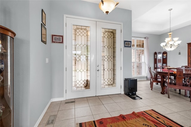 entrance foyer with a notable chandelier, light tile patterned flooring, and french doors