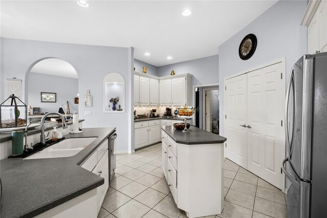 kitchen featuring light tile patterned flooring, sink, white cabinetry, stainless steel appliances, and a center island