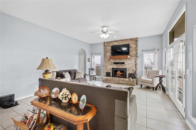 tiled living room with a fireplace and ceiling fan