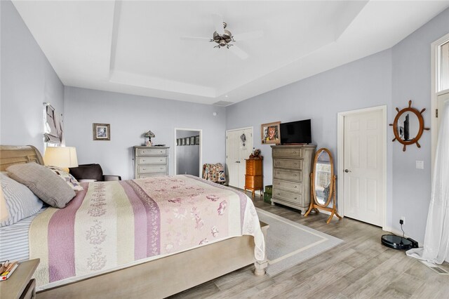 bedroom with a tray ceiling, ceiling fan, and hardwood / wood-style flooring