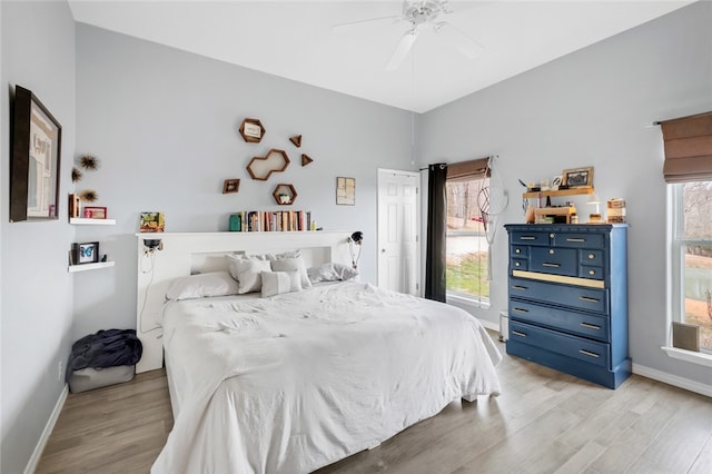 bedroom with ceiling fan, light hardwood / wood-style flooring, and multiple windows