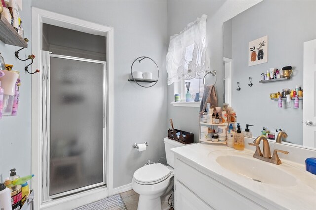 bathroom featuring a shower with door, toilet, vanity, and tile patterned floors