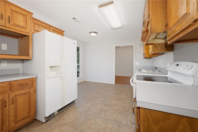 kitchen featuring light tile patterned flooring, a textured ceiling, white appliances, and sink