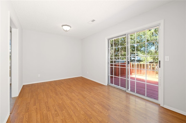 unfurnished room featuring light hardwood / wood-style floors and a textured ceiling