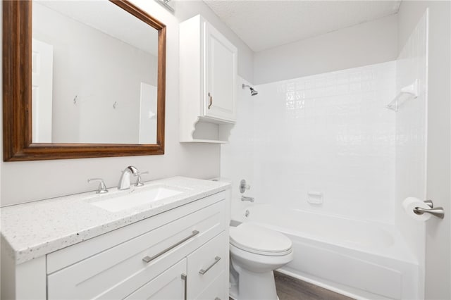 full bathroom with vanity, a textured ceiling, washtub / shower combination, hardwood / wood-style floors, and toilet