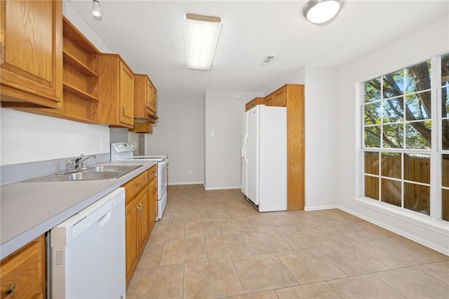 kitchen featuring a textured ceiling, white appliances, and sink