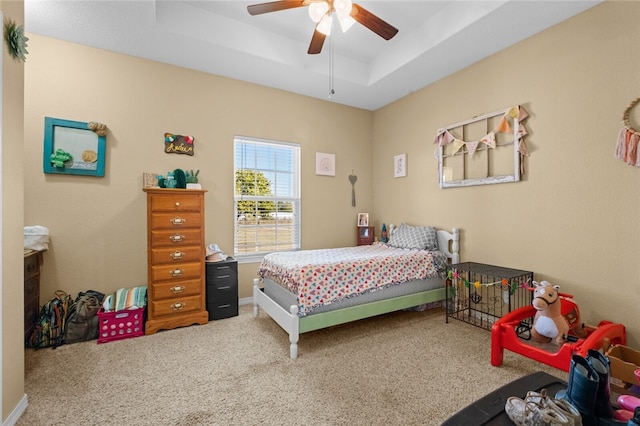 carpeted bedroom with a tray ceiling and ceiling fan