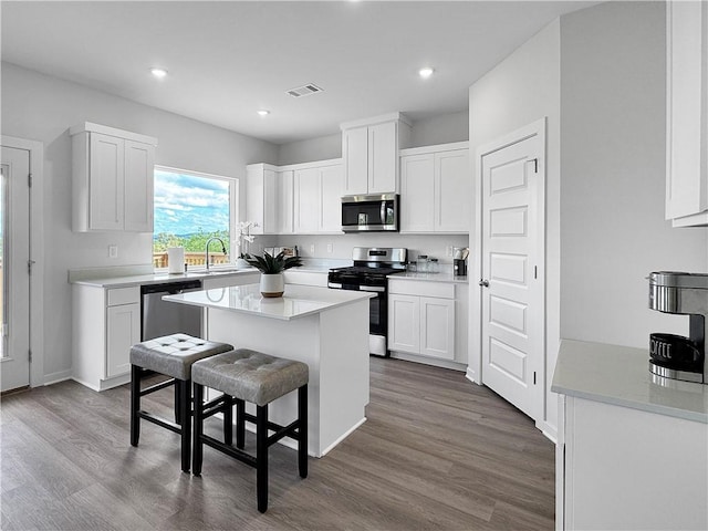 5395 Selah St, Springdale, AR 72764 - kitchen with stainless steel appliances, a breakfast bar, a kitchen island, white cabinets, and dark wood-style floors