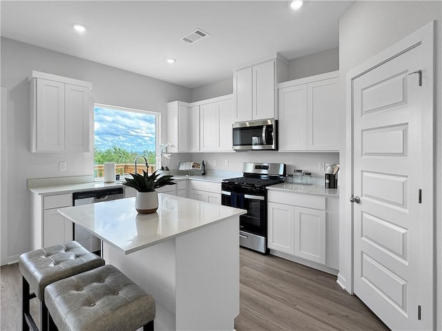 5395 Selah St, Springdale, AR 72764 - kitchen featuring stainless steel appliances, a kitchen bar, a center island, wood finished floors, and white cabinetry