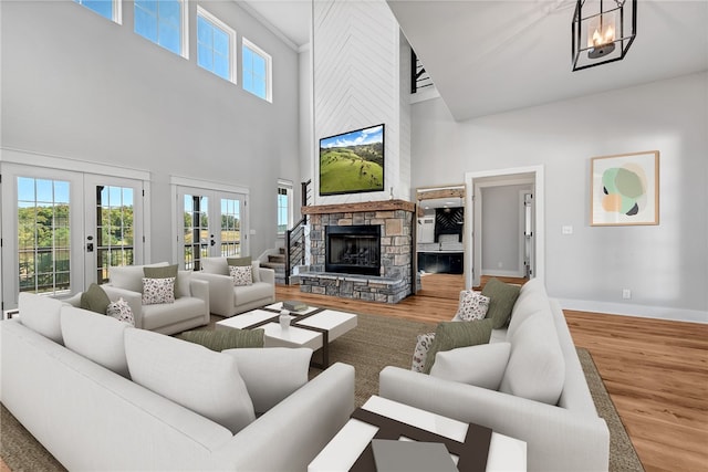 living room with a high ceiling, hardwood / wood-style floors, a fireplace, and french doors