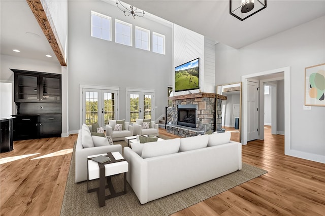 living room featuring french doors, beam ceiling, hardwood / wood-style floors, and a high ceiling