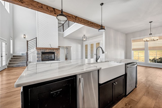 kitchen with appliances with stainless steel finishes, an island with sink, and decorative light fixtures