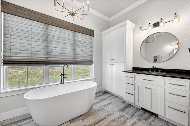 bathroom with an inviting chandelier, vanity, a bathtub, and crown molding