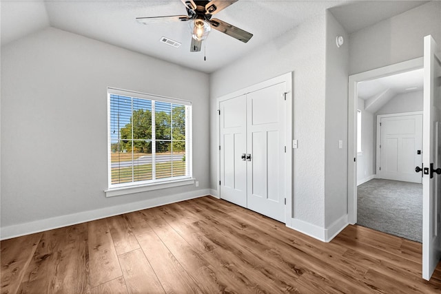 unfurnished bedroom featuring a closet, vaulted ceiling, ceiling fan, and hardwood / wood-style flooring