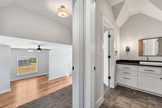 bathroom featuring wood-type flooring, a textured ceiling, lofted ceiling, ceiling fan, and vanity