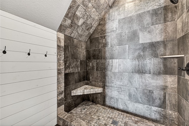 bathroom featuring lofted ceiling, a textured ceiling, and tiled shower