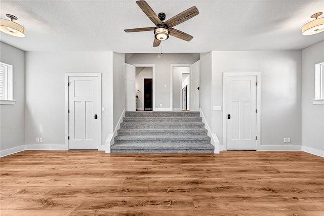 stairs with wood-type flooring, a textured ceiling, plenty of natural light, and ceiling fan