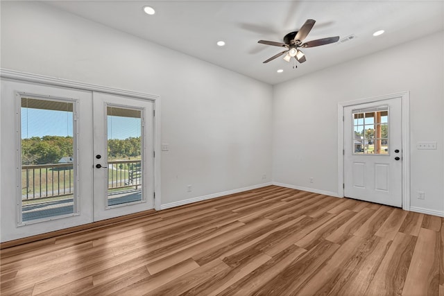 empty room with french doors, light wood-type flooring, and ceiling fan