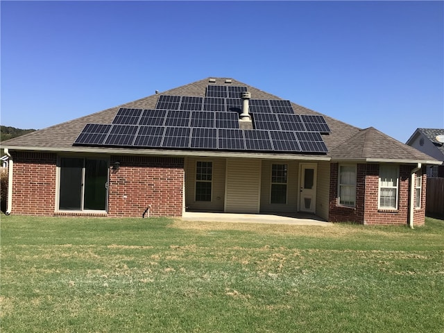 back of house featuring a patio, a lawn, and solar panels