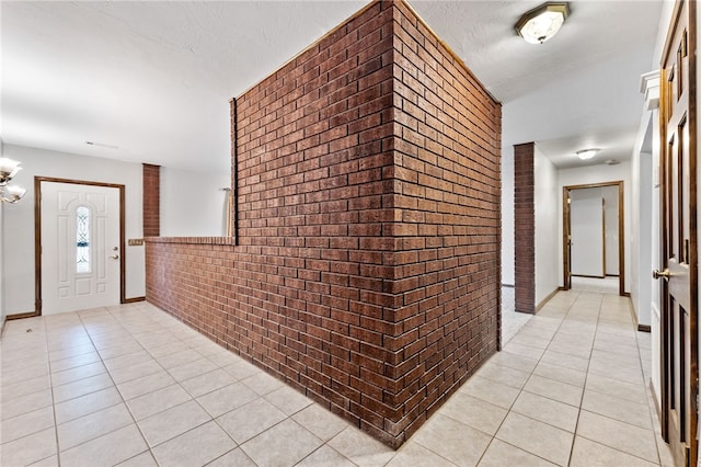 foyer entrance featuring light tile patterned floors and brick wall