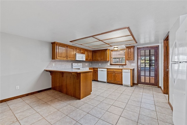 kitchen with white appliances, light tile patterned floors, tasteful backsplash, kitchen peninsula, and a breakfast bar area