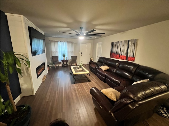 living room featuring a large fireplace, ceiling fan, and dark hardwood / wood-style flooring