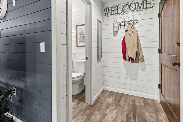 bathroom featuring wooden walls, hardwood / wood-style flooring, and toilet