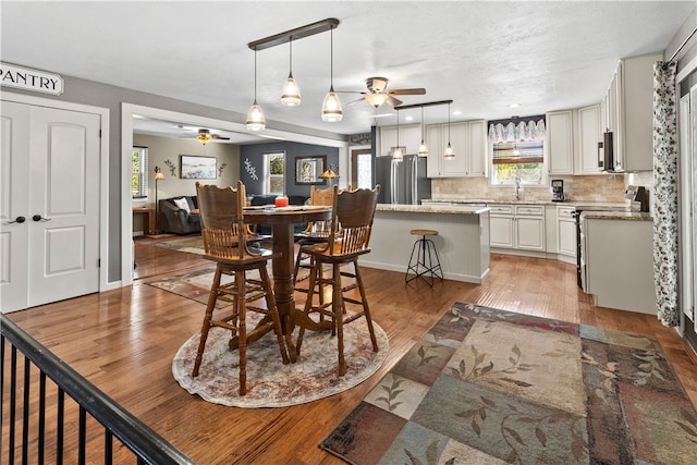 dining space featuring ceiling fan, sink, and hardwood / wood-style floors