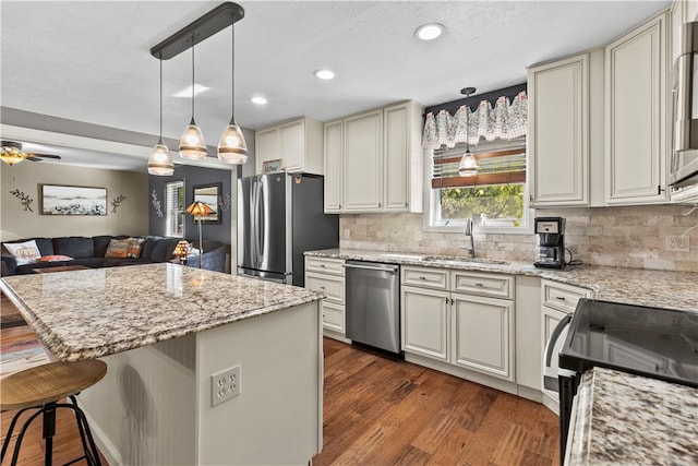 kitchen featuring dark hardwood / wood-style flooring, appliances with stainless steel finishes, a kitchen breakfast bar, sink, and a center island