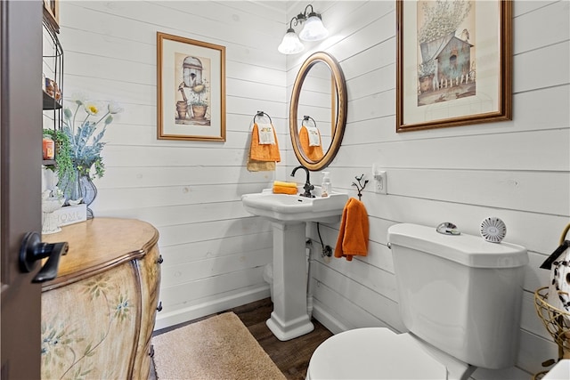 bathroom featuring toilet, wood walls, and hardwood / wood-style floors