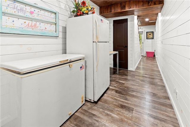 kitchen with wood walls, white fridge, and dark hardwood / wood-style flooring