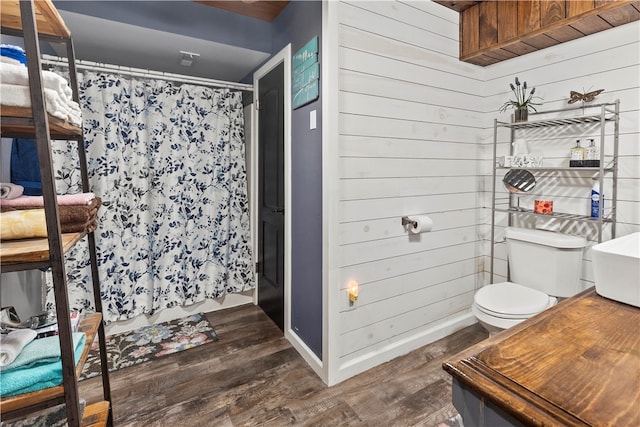 bathroom with toilet, wood walls, and hardwood / wood-style floors