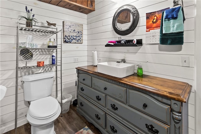 bathroom with vanity, toilet, wood walls, and hardwood / wood-style floors