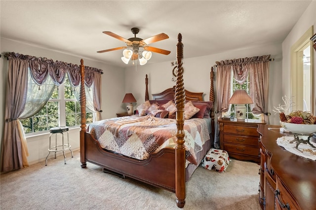 bedroom with multiple windows, ceiling fan, and light colored carpet