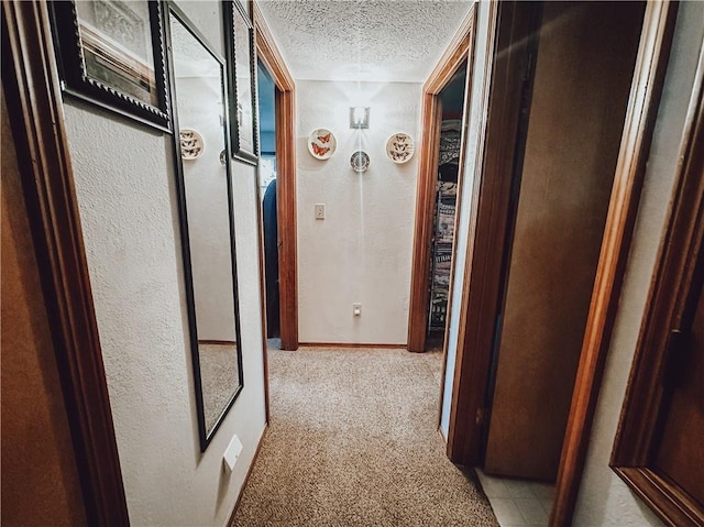 hallway with light colored carpet and a textured ceiling